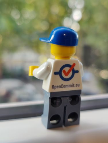 A LEGO minifigure wearing an OpenCommit.eu shirt, standing on a windowsill